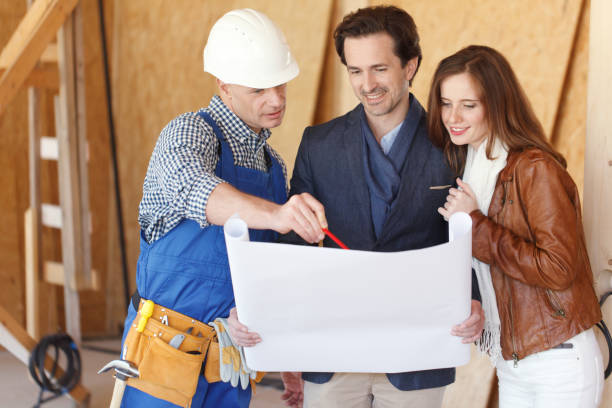 Foreman and couple with blueprint stock photo