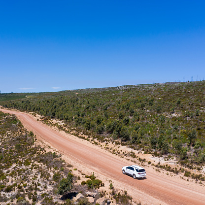 A white Toyota Fortuner driving along a gravel road on the farm. High angle view of a Toyota driving along a gravel road in the mountains