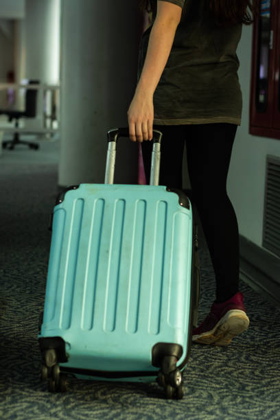 istock Young woman carrying blue suitcase 1209601317