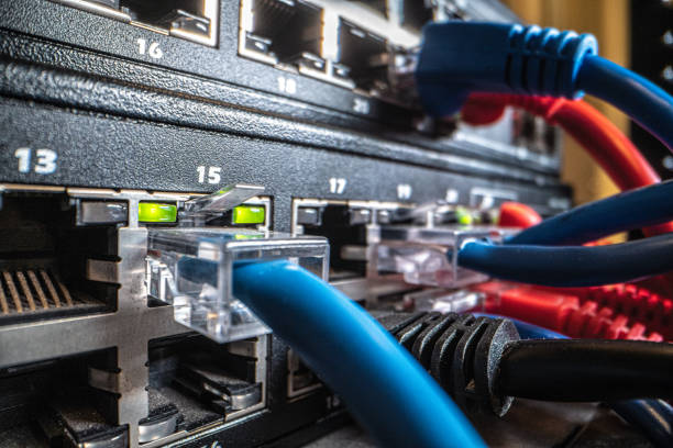 ラックに取り付けられたネットワーク スイッチ機器ハードウェアに接続された青 cat5e イーサネット ケーブル コネクタのクローズアップ ショット - messy network server cable computer ストックフォトと画像