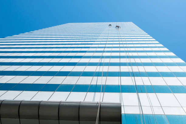 istock Group of workers cleaner cleaning windows on high rise building skyscraper  over blue sky 1209604364