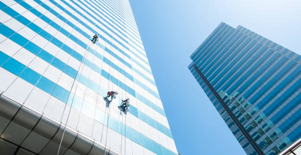 istock Group of workers cleaner cleaning windows on high rise building skyscraper  over blue sky 1209604402