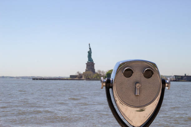 binóculos turísticos na ilha ellis com estátua da liberdade visíveis no fundo desfocado. há um céu azul e água visível. o metal mostra a idade e é queimado - statue liberty statue of liberty ellis island - fotografias e filmes do acervo