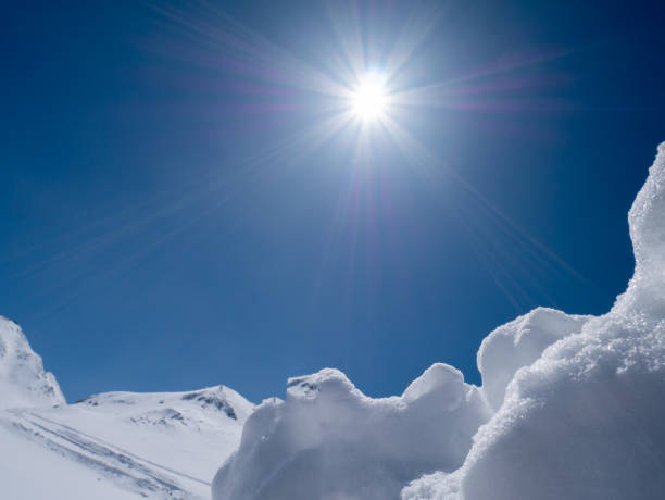 Mountain summit in the Austrian Alps. View on the Kaiser mountains with summit cross and ski in the foreground.