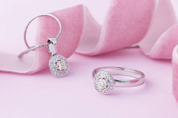 elegancki zestaw biżuterii z białego złota naszyjnik i pierścionek z diamentami na pastelowym różowym tle - charm necklace zdjęcia i obrazy z banku zdjęć