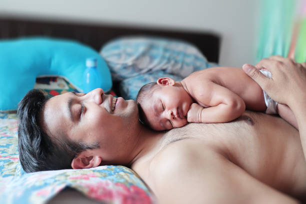 un bebé en cuerpo desnudo durmiendo pacíficamente en el cuerpo en su padre. concepto de paternidad crianza foto - baby cute selective focus close up fotografías e imágenes de stock