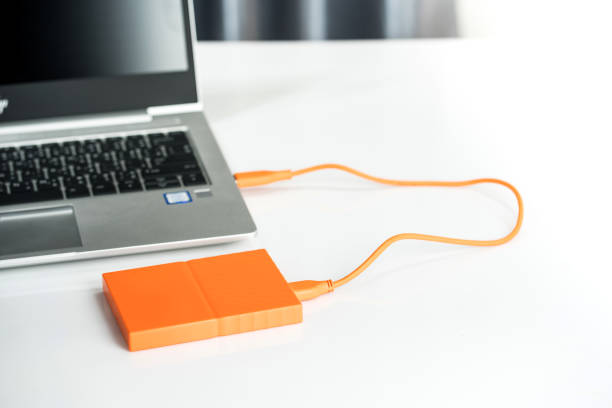 istock Close up of external hard disk drive for connect to laptop, transfer or backup data between computer and HDD. Black hard disc for backup files and important information using USB 3.0 connection 1209624589