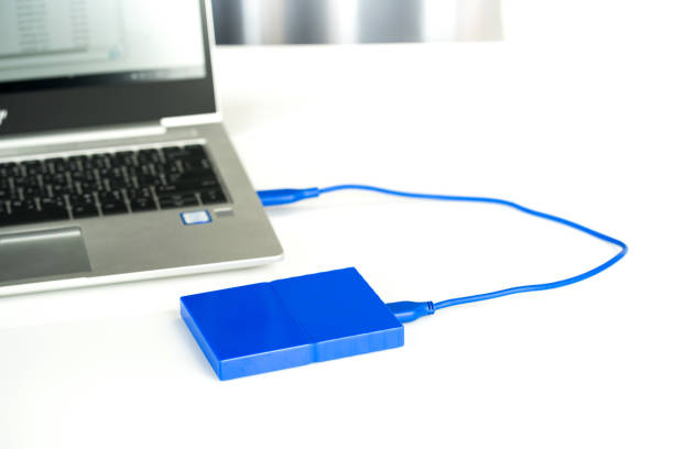 istock Close up of external hard disk drive for connect to laptop, transfer or backup data between computer and HDD. Black hard disc for backup files and important information using USB 3.0 connection 1209624590