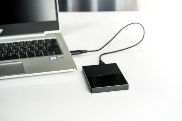 istock Close up of external hard disk drive for connect to laptop, transfer or backup data between computer and HDD. Black hard disc for backup files and important information using USB 3.0 connection 1209624591