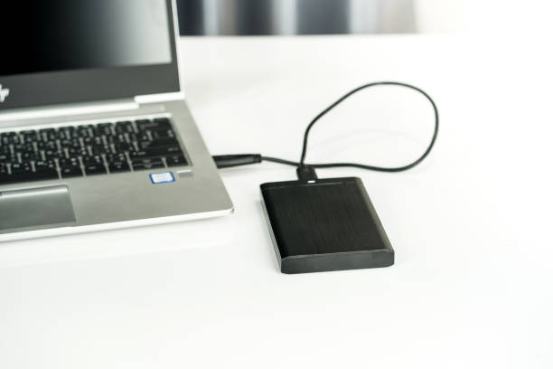istock Close up of external hard disk drive for connect to laptop, transfer or backup data between computer and HDD. Black hard disc for backup files and important information using USB 3.0 connection 1209624601