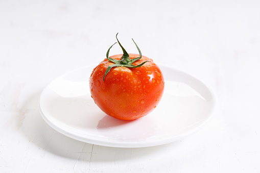 fresh whole tomato on white wooden background