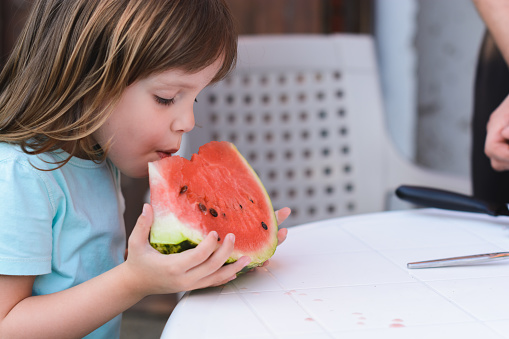 Cute little girl eating watermelon outdoors