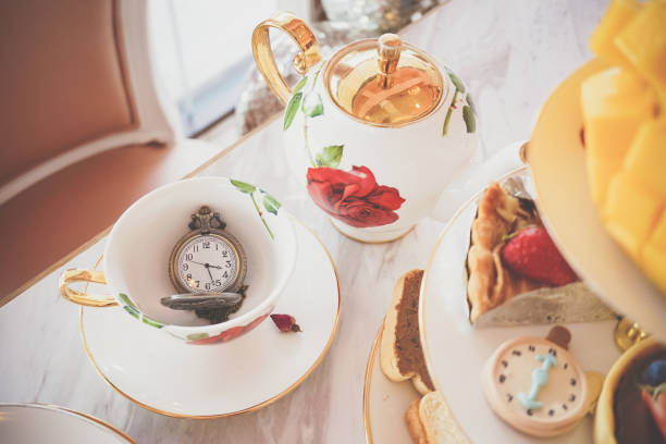 Tea time. A traditional afternoon tea time with selective focus on the classic pocket watch. Vintage filter and window light. A classic British tea time is served around 3.30 - 5.00 pm.
