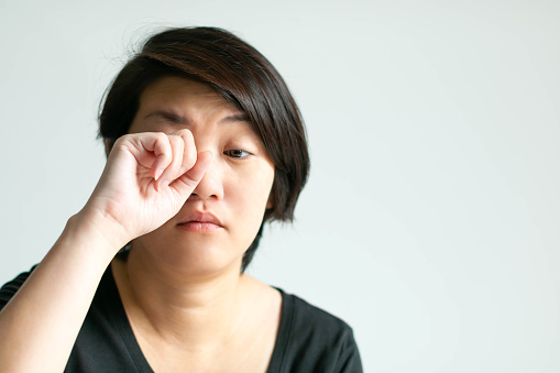 Close-up of woman use hand rubbing her eye with sleepy face. Concept of health care and medical.