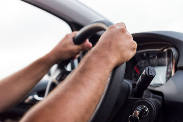 istock young man hands driving a car with both hands on the wheel 1209630004
