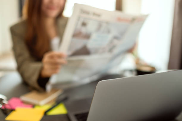 istock A business woman reading newspaper while working i 1209631339