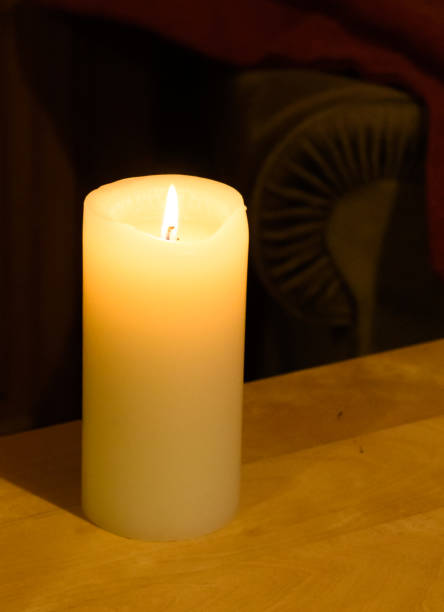 istock A lit wax pillar candle burning, lighting a room 1209632532
