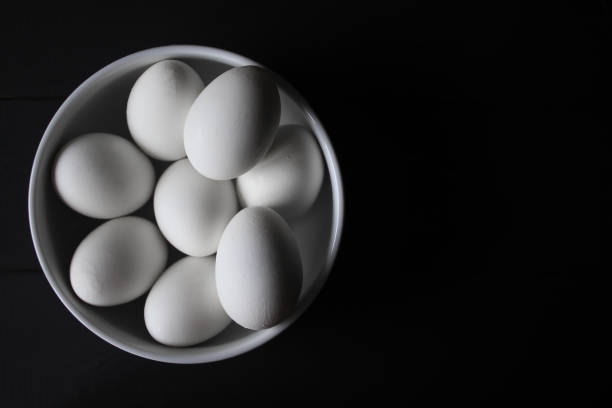 istock White eggs in a white plate, on a black background. Healthy food concept. 1209633327