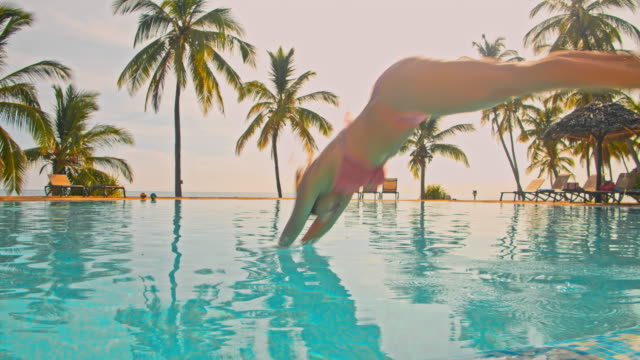 SLO MO Woman jumping into the pool of a luxury beach resort