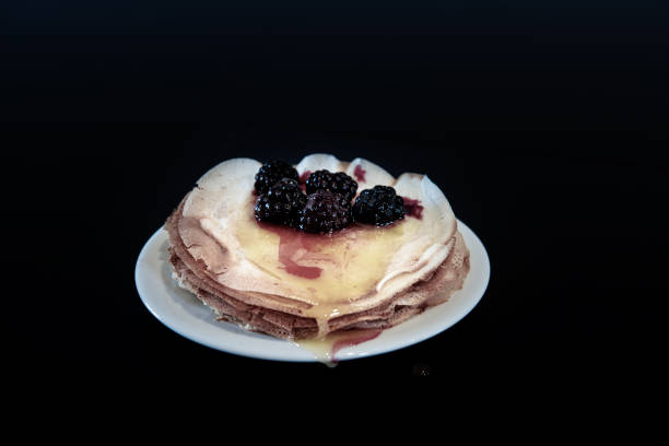 istock Stack of thin pancakes poured with honey and decorated with fresh blueberries side view with selective focus and dark background with copy space 1209639303