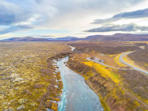 Photo of Hraunfossar series of waterfalls barnafoss aerial image of turquoise water streaming down gaps in lava fields and collecting in river