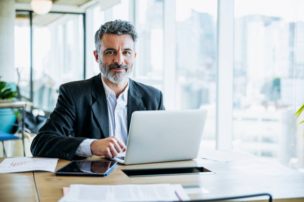 istock Smiling bearded businessman working on laptop in office 1209643272