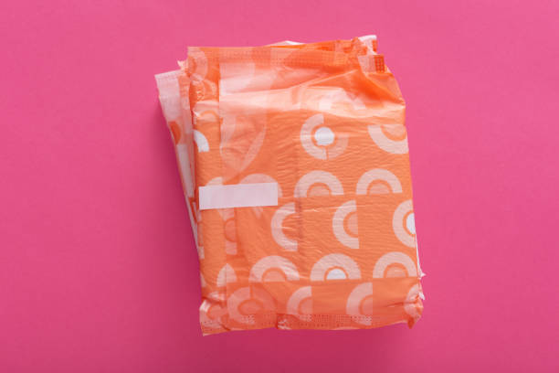 istock Image of several hygiene pads, being packed in colorful package lying isolated over pink background. Critical days. Menstrual pad for hygiene during blood period. Flat lay composition concept. 1209644406