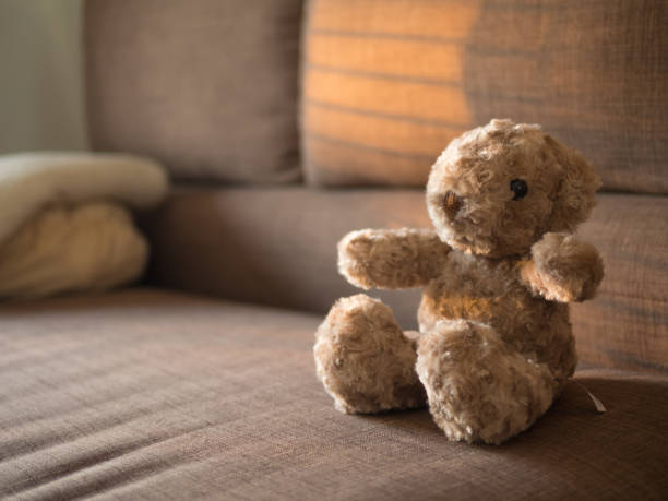istock Lonely teddy bear sit on the fabric sofa under warm light . 1209650383