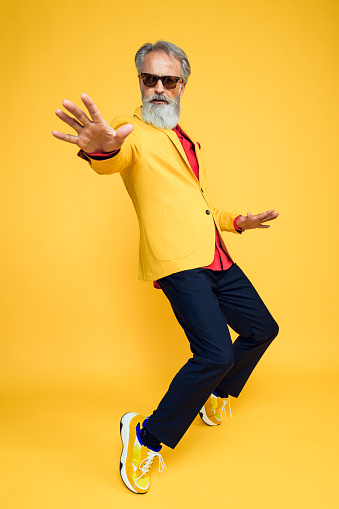 Portrait of senior man wearing yellow jacket on yellow background. Styled, well dressed man.