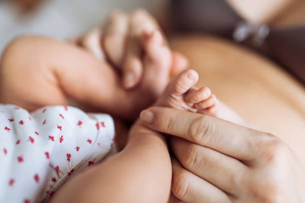 istock Post partum mother body holding baby's small feet 1209655238