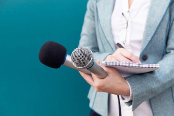 news reporter or tv journalist at press conference, holding microphone and writing notes - journalist imagens e fotografias de stock