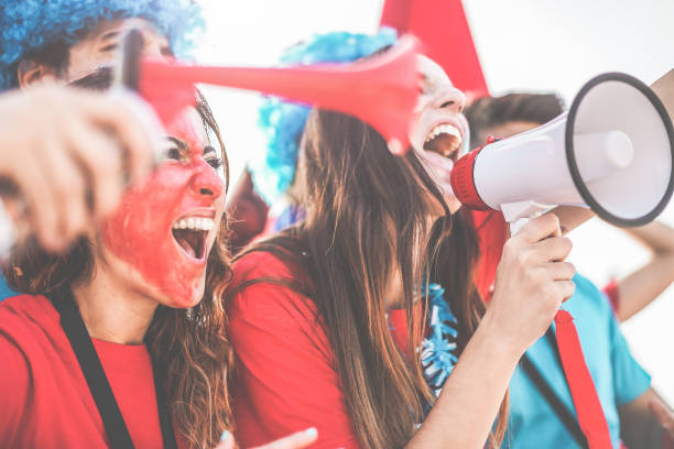 istock Crazy sport fans screaming while supporting their team - Football supporters having fun inside stadium for soccer match - Event concept - Focus on right man face - Focus on speaker 1209659740