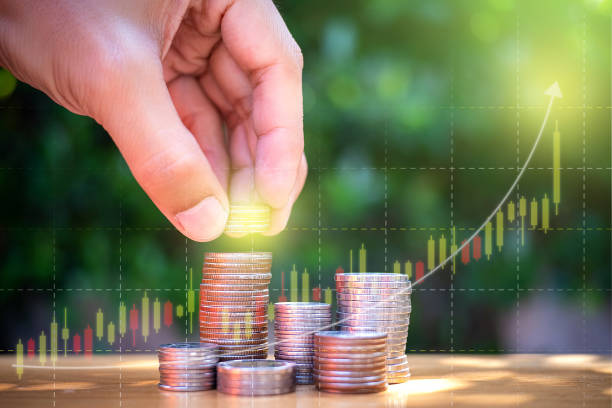 istock Coin stack with man left hand want to put coin and investing graph background. Saving for the future. Close up shot. 1209661040