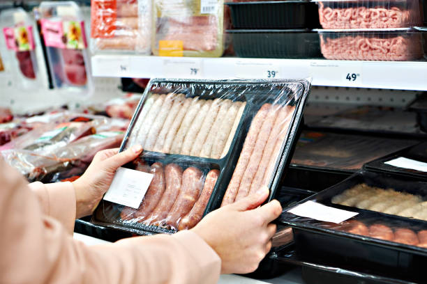 mujer elige salchichas en paquete de vacío en la tienda - supermarket meat women packaging fotografías e imágenes de stock