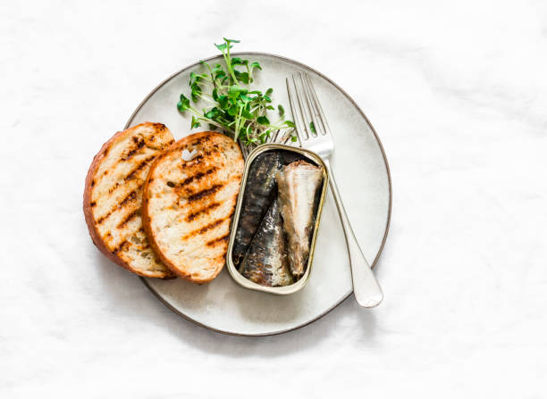 istock Grilled bread, canned sardines, micro greens on a light background, top view. Delicious breakfast, tapas, appetizers 1209663923