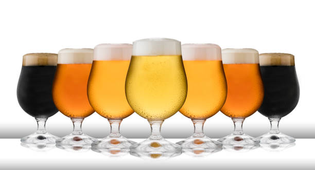 una fila di lager rinfrescante, birra, sidro e robusto, in bicchieri da goletta, con condensa, su un tavolo bianco e sfondo bianco - amber beer foto e immagini stock