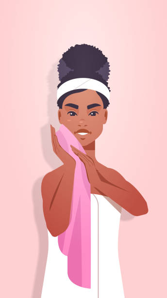 african american kobieta czyszczenie twarzy z różowym ręcznikiem dziewczyna wycieranie twarzy skóry skóry pielęgnacja spa koncepcja leczenia pionowa - clear sky human skin towel spa treatment stock illustrations