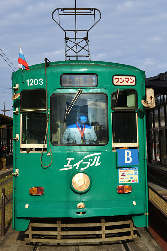 Train attendant with facemask to protect from polution and viruses such as Corona Virus on a sunny day in Tokyo, Japan