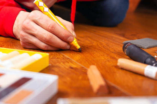 repair restoration laminate flooring parquet and wood products.sealing scratches and chips. master processes the surface with a special pencil to remove scratches close-up stock photo