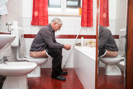 Hombre Adulto Mayor defecando en el baño doméstico photo