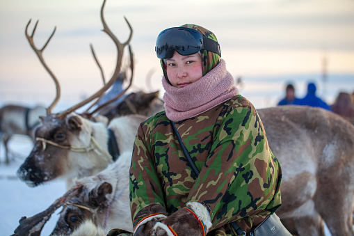 Far North, Península de Yamal, Día del Reno Herder, residentes locales vestidos de Nenets, asistente de criadores de renos, niña con gafas de esquí y ropa de camuflaje photo