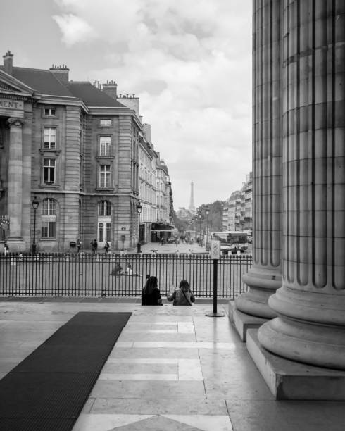 This is a photography of two people on the steps of the Pantheon looking out at the Eiffel Tower in Paris, France.