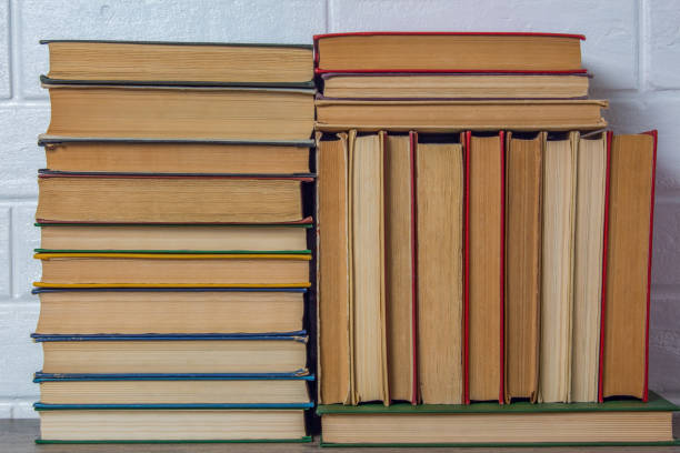 istock A stack of old books. Bookstore, library, bookshelf. Vintage, retro, antique.  Study, education, school, University. Literature, history, science. Books against a white brick wall. 1209667778