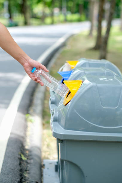 istock Hand put plastic bottle to the gray bin in park or garden with day light 1209669130