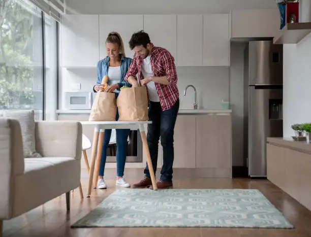 Photo of Couple unpacking groceries at home