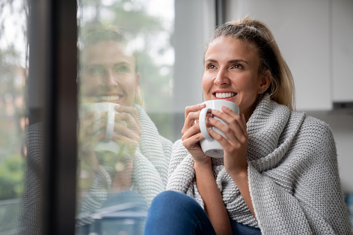 Portrait of a thoughtful woman drinking a cup of coffee at her cozy home â lifestyle concepts
