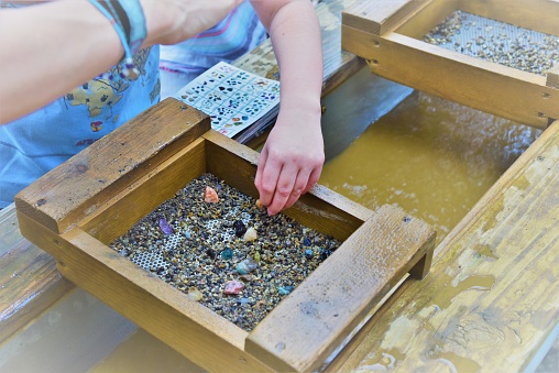 A photos showing a child's hand using a gold sifter panning for gold and gems a great educational outdoor acitivity with kids
