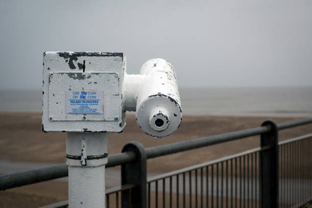 Binoculars at the pier in Scheveningen. Focus on the foreground, blurred background. Sunset, warm light, tranquil scene. The Hague, Netherlnds.
