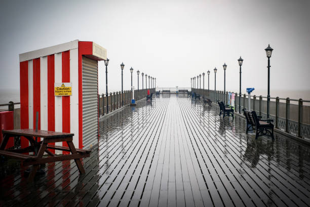 Skegness, Lincolnshire, UK: August 18th 2015. Holidaymakers and daytrippers make the best of the bad weather, Heavy rain all day on the promenade resulting in empty beaches, but indoor amusements are doing well.