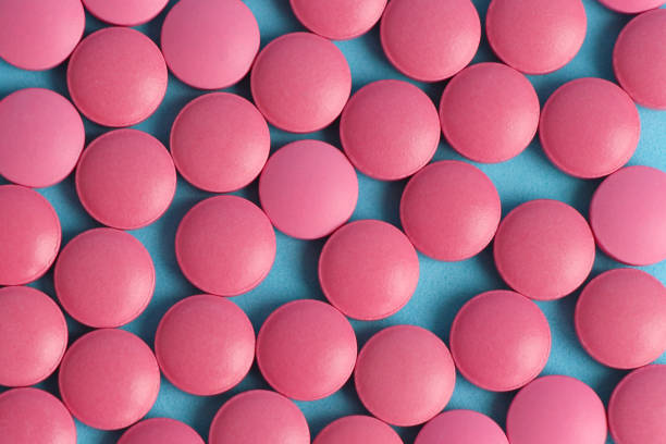 istock Group of pink round pills on a blue background 1209678171